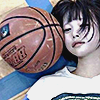 aesthetic photo of a model laying on a gym floor with a basketball next to her head