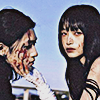 aesthetic photo of two mdoels, one with a bloodied face, and the other holding that person by the chin and looking into the camera