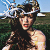 aesthetic photo of a model with a floral branches type crown atop her head in a grass field