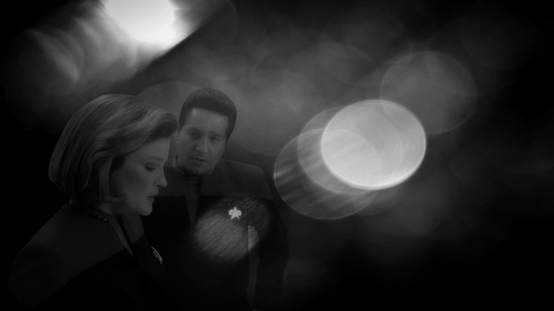 Kathryn and Chakotay looking fragile staring past each other in Equinox against a greyscale bokeh lights background