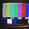 CRT television in a dark room showing the default color bars