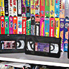 VHS tapes stacked on a shelf together and two not sleeved in front for display