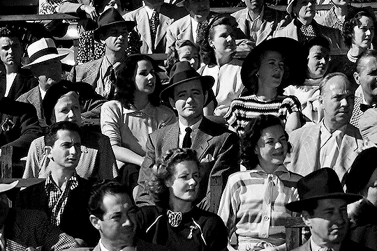 Crowd looking from right to left, with a single person staring forwards