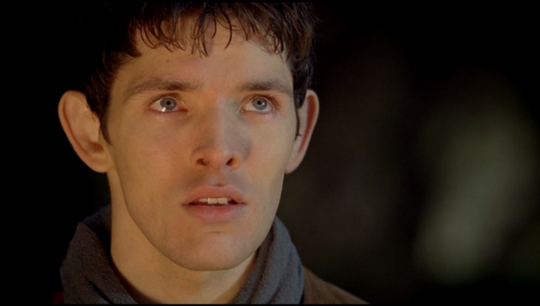 a shot of Merlin bathed in light looking at Arthur with a reverent look as Arthur pulls the sword from the stone.