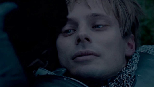 a close up shot of Arthur staring up at Merlin as he dies
