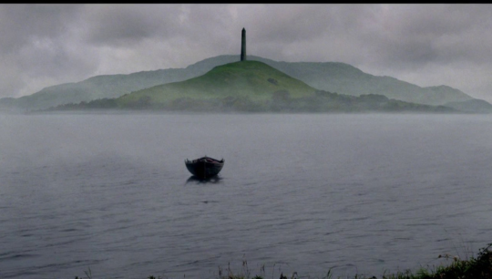 a far away shot of the boat in the middle of Lake Avalon as it carries Arthurs body away