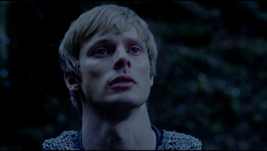 a picture of Arthur looking up with a regretful and reverent look on his face, the lighting is pale