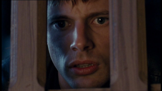 a shot of Arthur staring between two wooden slats with a shocked heart broken look on his face as Morgana is crowned queen