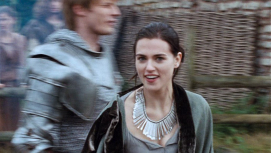 a picture of Morgana grinning in Eriador after she has saved Arthur from an attack with Arthur in the background blurry