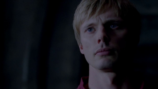 a picture of Arthur half in shadow looking very sad and serious as he stares off camera 