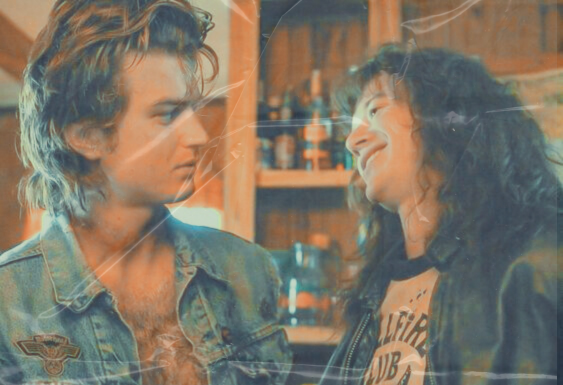 a picture of Eddie tilting his head and grinning at Steve while they are in Maxes trailer and Steve is staring back at Eddie looking confused there is a filter on the photo that makes it look like a creased photograph.
