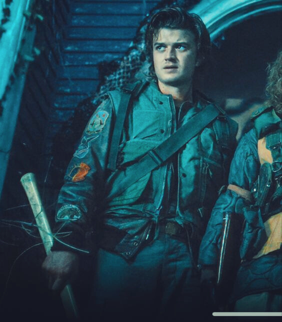 a picture of steve as they stand outside the creel house in the upside down after they have fought vecna and he is looking out into the distance looking determined and angry as he holds his axe.