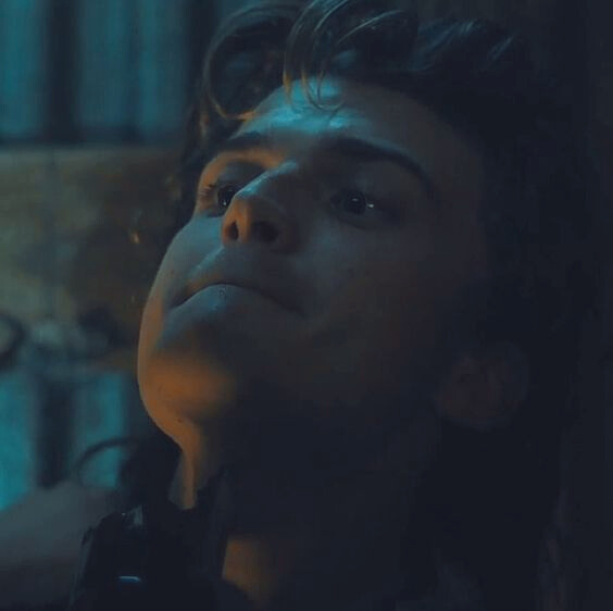 a close up picture of Steves face as he leans his head back against the wall of the shed and Eddie holds the broken bottle against his throat.