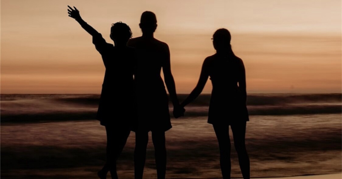 A man with two women watch the beach.