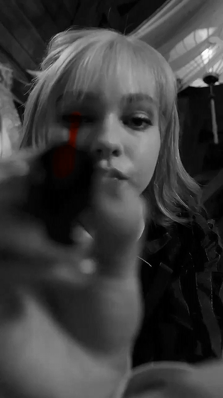 Enid in black and white painting blood red nail polish on the screen