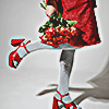 stock photo of a person in a red dress from the skirt down, leg bent and in the air while they hold red flowers