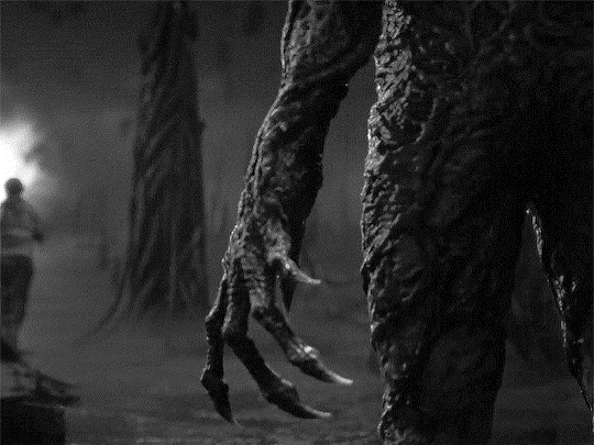 Creepy clawed hand with someone running away in the background