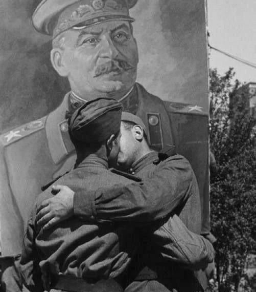 image of two Red Army soldiers sharing a Soviet kiss in front of a Stalin poster