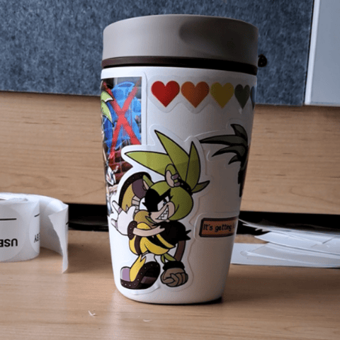 four images featuring a turnaround of the cup, one sticker has Surge making a dynamic breakdancing pose as she smirks at the viewer, another has a comically poorly-drawn Surge curled up in a fetal position and weeping, a third has her grinning, making a heart-shaped bolt of lightning with the colors of the bisexual pride flag, and a fourth has her making the sign of the horns as she makes graffiti.