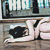 a woman laying on a wood floor, covering most of her face with her arm on the floor, knees presed to her chest