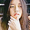 an asian woman with her hand on her chin looking off camera